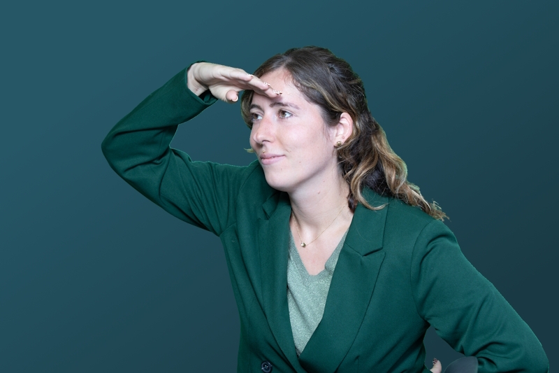 Een vrouw kijkt in de verte met haar hand boven haar ogen.