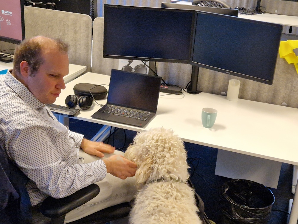 Bram sits at his desk with his dog Mellow next to him.