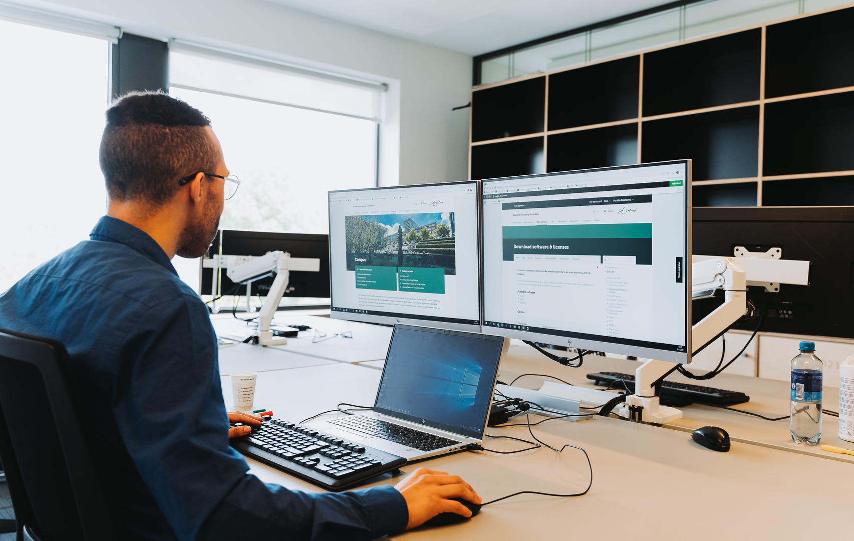 Man bekijkt website van Erasmus Universiteit op laptop met externe beeldschermen.